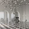 The Balloon Concerto Drums are set in a spacious, elegant room with checkerboard flooring and arched white doors. Dozens of metallic silver spheres of various sizes float like artistic balloons throughout the room, creating a surreal atmosphere reminiscent of a whimsical concerto.