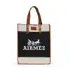 An Airmez tote bag with brown leather handles and trim, featuring a black canvas body adorned with a white horse and carriage illustration and the text 