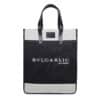 A black and white tote bag with black leather handles. The bag showcases the text 