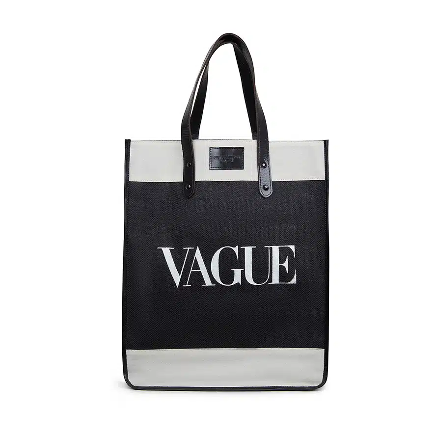 A black and white tote bag with leather handles. The Vague has a rectangular shape and features the word "VAGUE" prominently printed on the front in large white capital letters, capturing its essence perfectly.